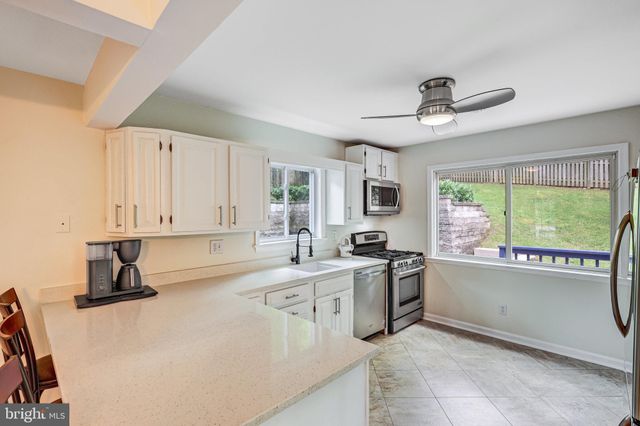 a kitchen with stainless steel appliances a stove a sink and white cabinets