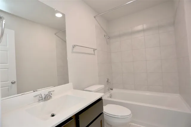 a bathroom with a bathtub shower sink vanity mirror and toilet