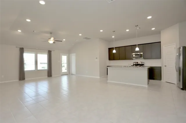 a view of an empty room with kitchen stove and cabinets