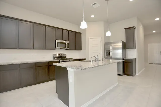 a kitchen with stainless steel appliances granite countertop a sink stove and refrigerator