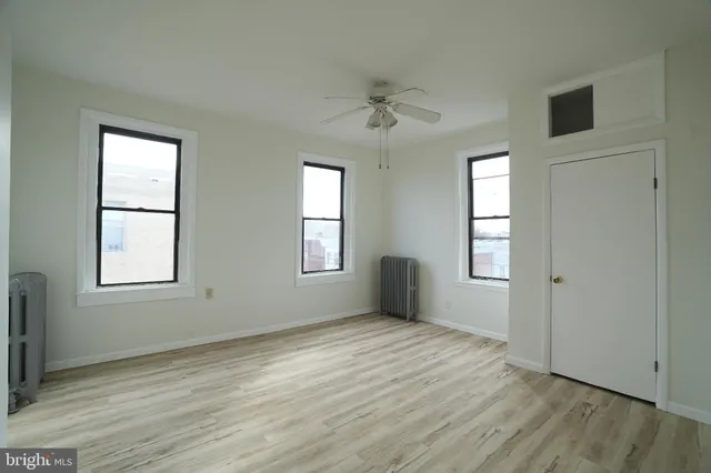 a view of an empty room with a window and wooden floor