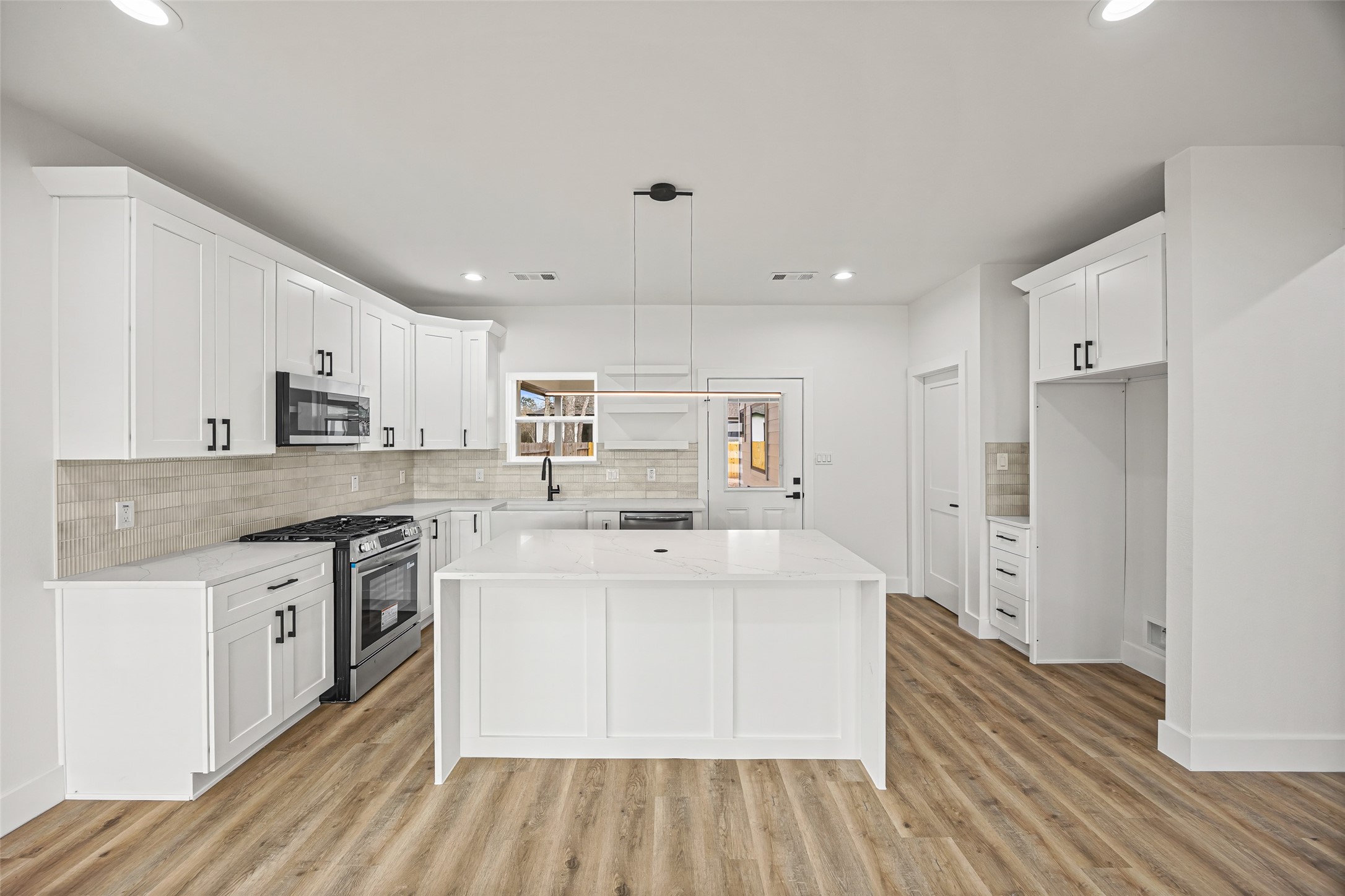 1807 Waco Street Dayton, TX 77535 - Photo 5 of 26 Modern kitchen featuring a large center island, quartz countertops, stainless steel appliances, and shaker-style cabinetry.