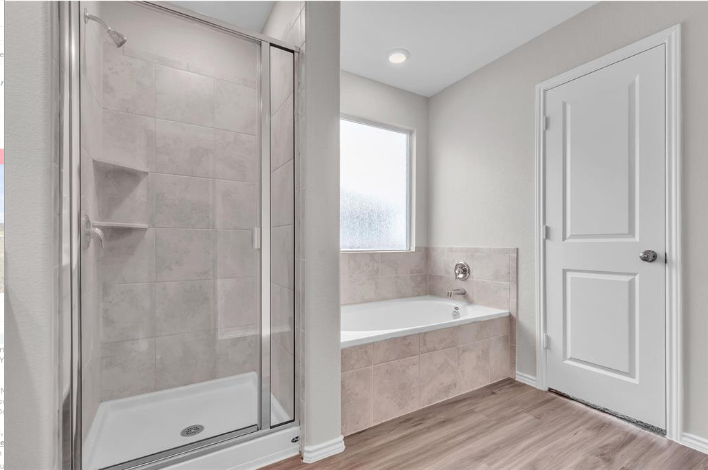 240 Madrid Kyle, TX 78640 - Photo 18 of 25 Full bathroom featuring a stall shower, a garden tub, and wood finished floors