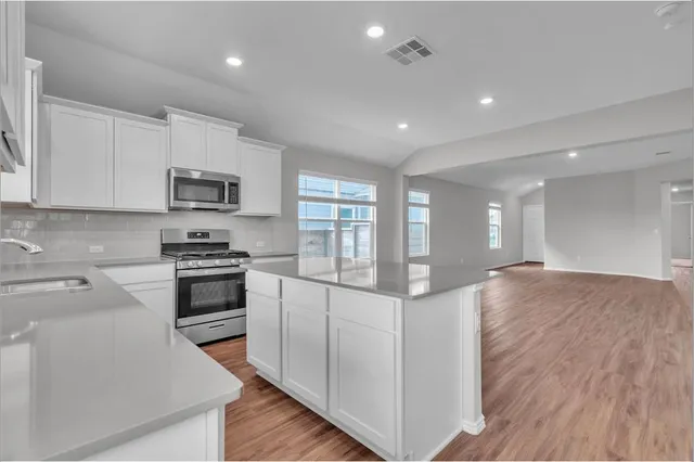 a kitchen with microwave a stove and cabinets