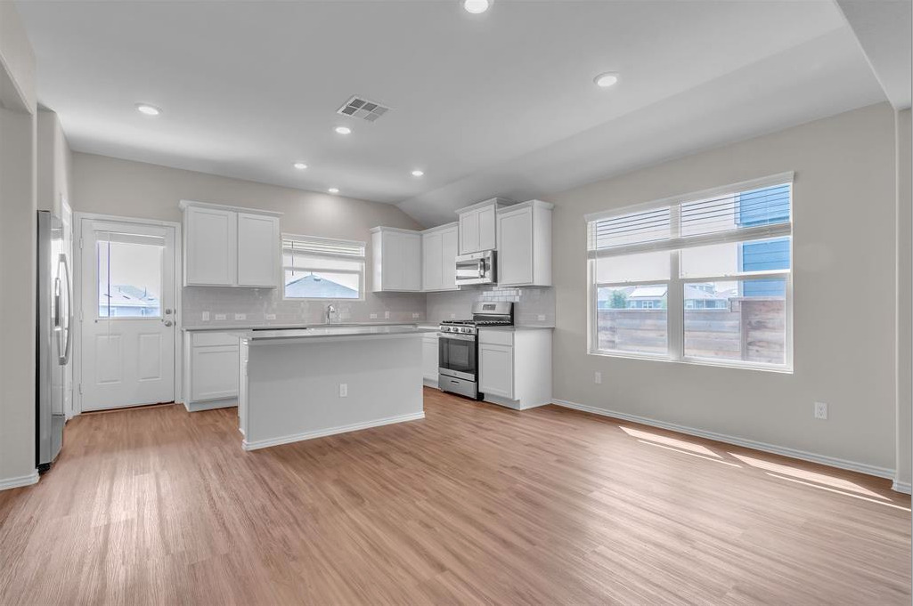 240 Madrid Kyle, TX 78640 - Photo 6 of 25 Kitchen with stainless steel appliances, light wood-type flooring, a kitchen island, tasteful backsplash, and white cabinetry