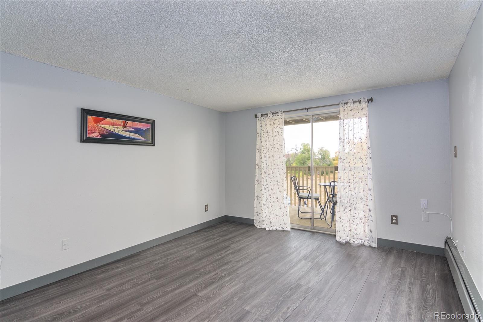 1304 South Parker Road, Unit 347 Denver, CO 80231 - Photo 5 of 27 an empty room with wooden floor and windows