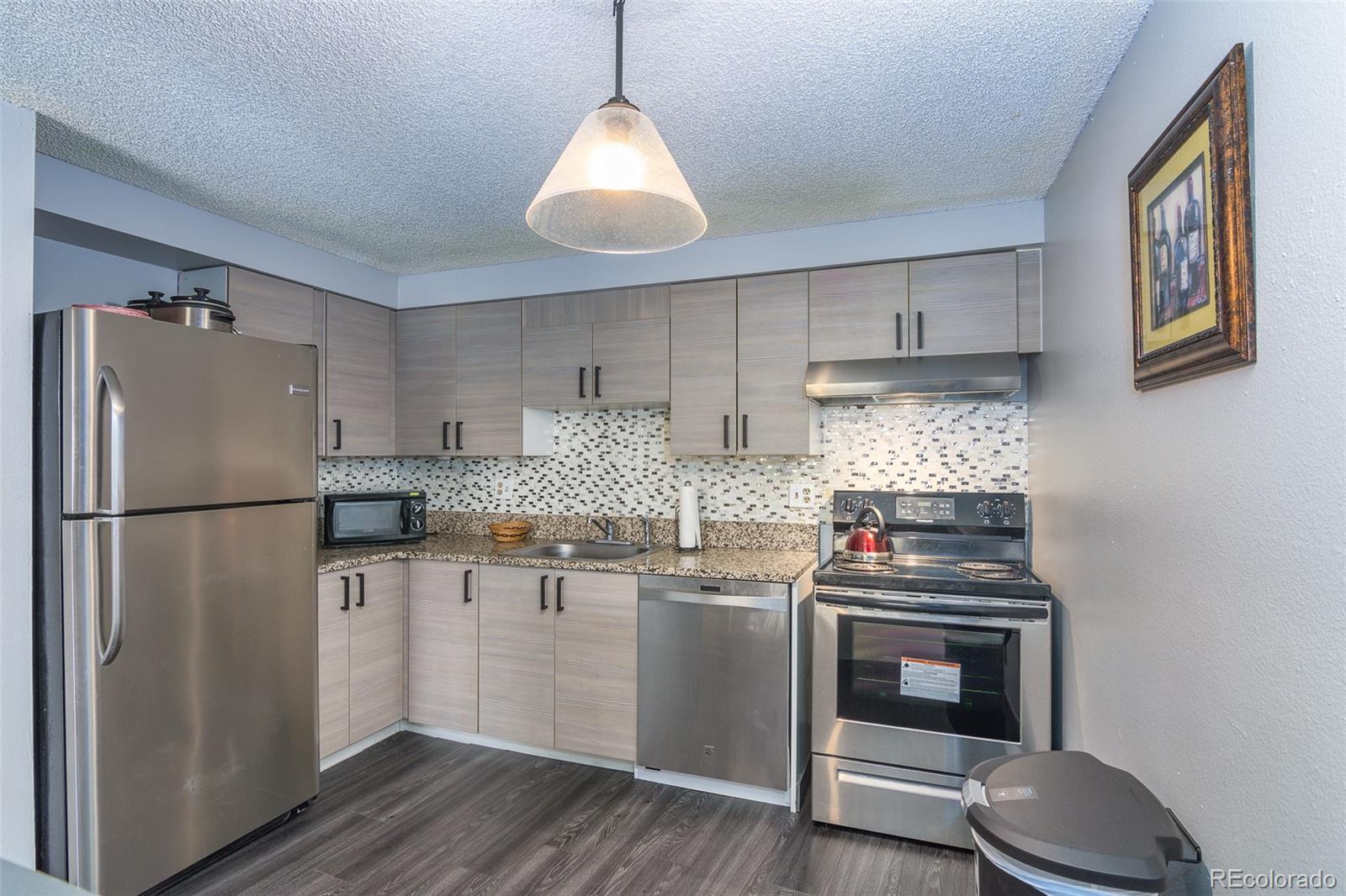 1304 South Parker Road, Unit 347 Denver, CO 80231 - Photo 9 of 27 a kitchen with stainless steel appliances granite countertop a refrigerator a stove a sink and white cabinets with wooden floor
