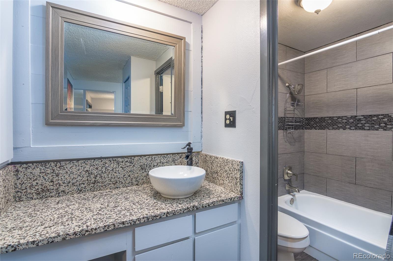 1304 South Parker Road, Unit 347 Denver, CO 80231 - Photo 10 of 27 a bathroom with a granite countertop sink a toilet and bathtub