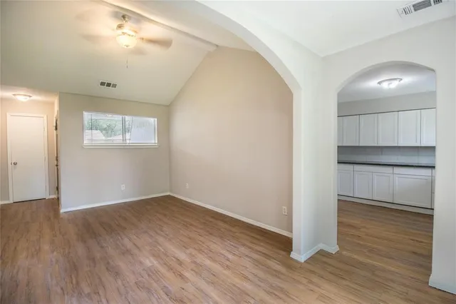 an empty room with wooden floor cabinet and windows