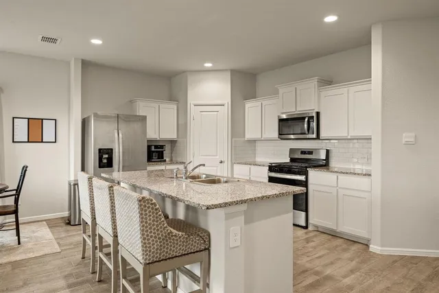 a kitchen with stainless steel appliances granite countertop a table chairs sink refrigerator and microwave