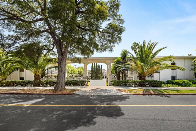 a front view of multi story residential apartment building with yard and sign board