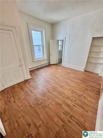 a view of an empty room with wooden floor and stairs