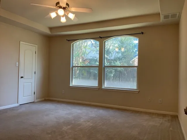 an empty room with a window and a ceiling fan