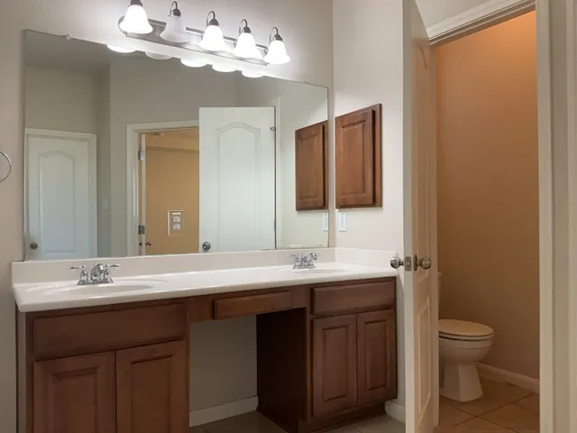 a bathroom with a double vanity sink mirror and toilet