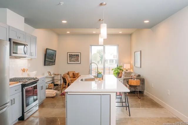 a room with stainless steel appliances a dining table wooden floor and a view of living room