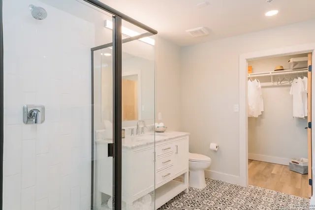 a bathroom with a granite countertop sink a toilet a mirror and shower