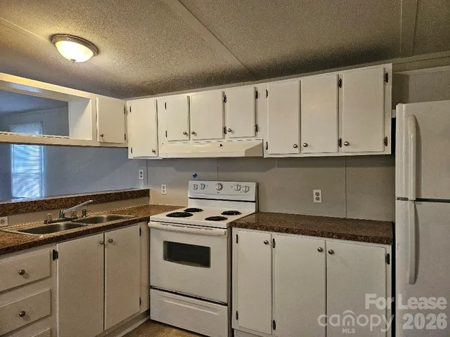 a kitchen with granite countertop white cabinets and white appliances