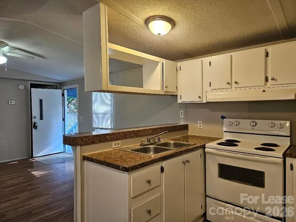 a kitchen with granite countertop a stove sink and cabinets
