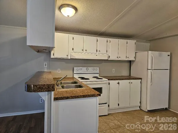 a kitchen with granite countertop a refrigerator sink and cabinets