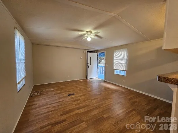 a view of an empty room with window and wooden floor