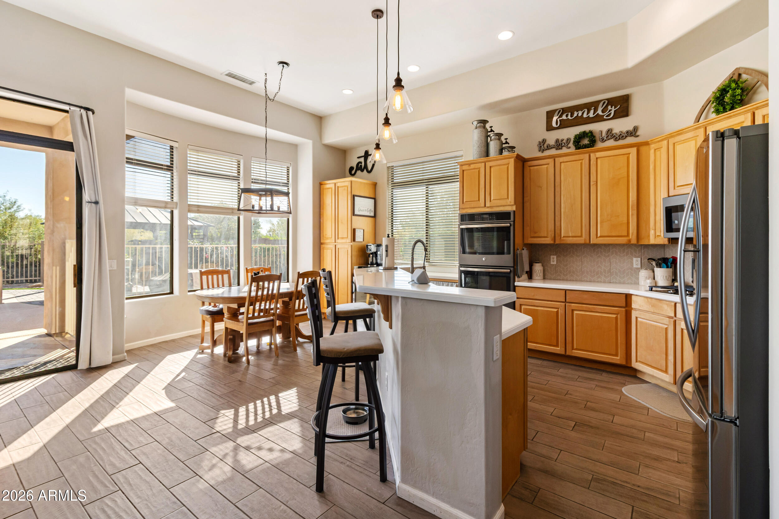 5219 East Hashknife Road Phoenix, AZ 85054 - Photo 10 of 38 a kitchen with stainless steel appliances kitchen island granite countertop a refrigerator a stove top oven and a dining table with wooden floor