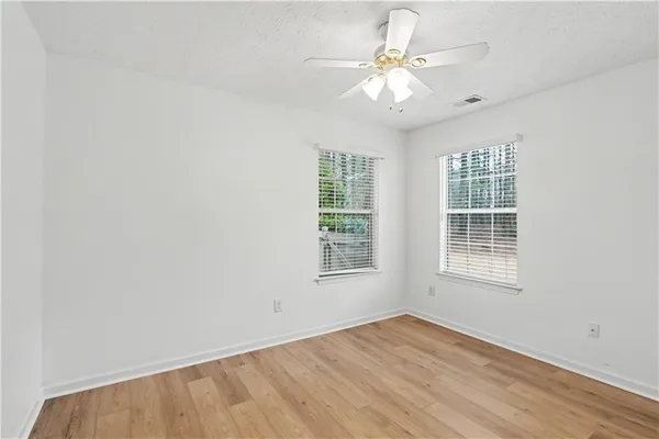 an empty room with chandelier fan and windows