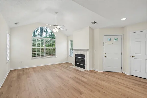 an empty room with windows a fireplace and wooden floor