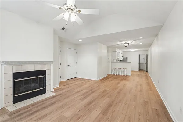 a view of an empty room with wooden floor fireplace and a window