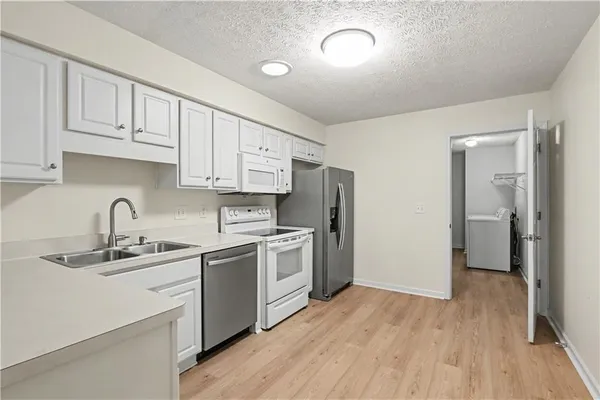 a kitchen with a sink cabinets stainless steel appliances and wooden floor