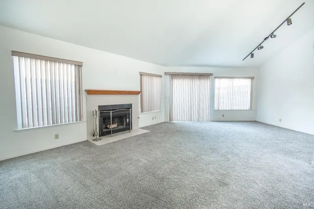 a view of an empty room with a window and fireplace