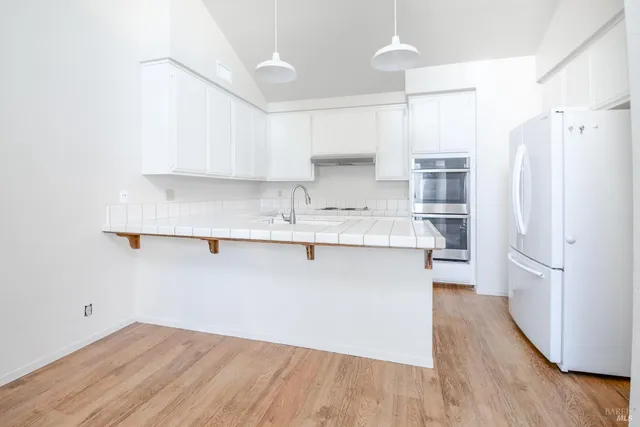 a kitchen with stainless steel appliances a refrigerator and a stove top oven