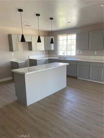 a view of an empty room with wooden floor and window