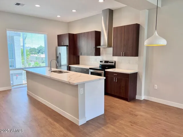 a kitchen with stainless steel appliances a sink a refrigerator and a window