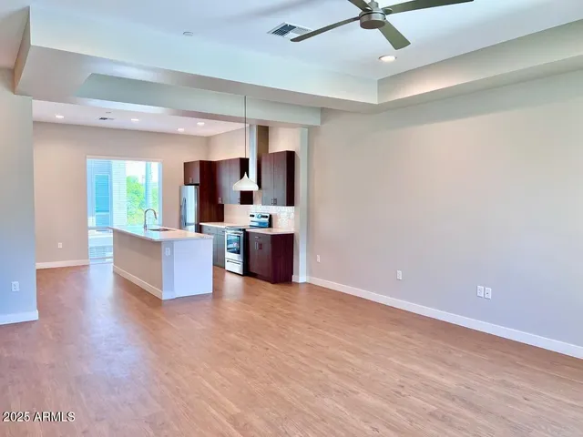 a living room with stainless steel appliances kitchen island furniture and a ceiling fan