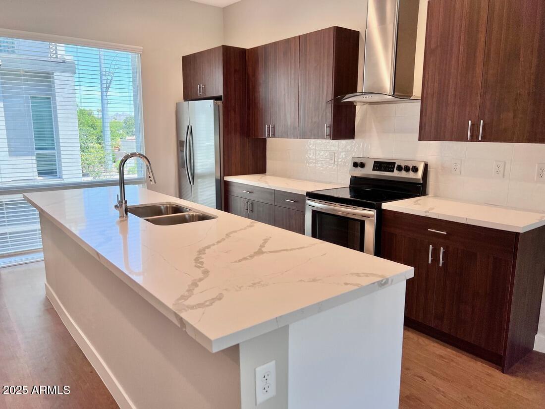 915 East Missouri Avenue, Unit 10 Phoenix, AZ 85014 - Photo 14 of 61 a kitchen with kitchen island wooden cabinets a refrigerator and a stove