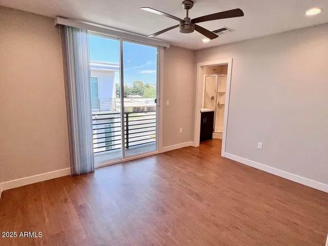 an empty room with wooden floor fan and windows