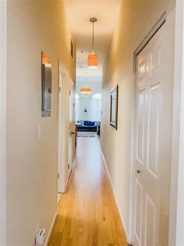 a hallway with wooden floor and cabinet