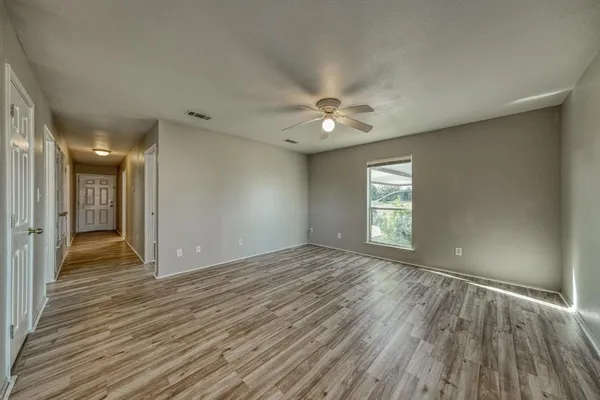 a view of an empty room with window and wooden floor