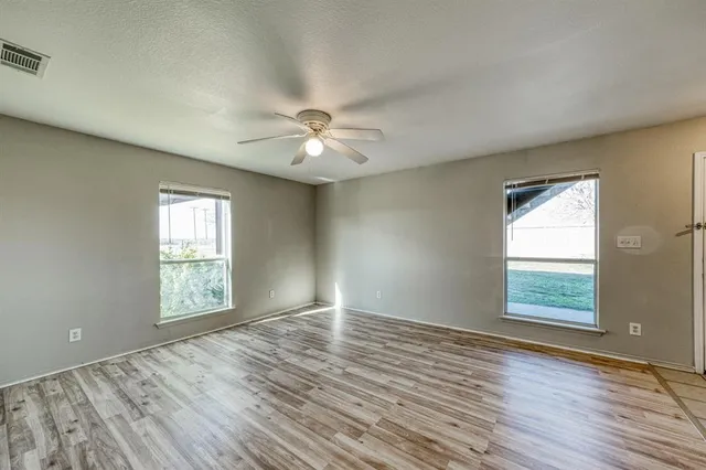 an empty room with wooden floor and windows
