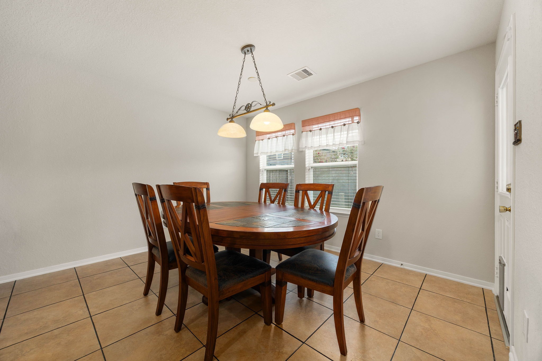 3102 Single Ridge Way Katy, TX 77493 - Photo 15 of 23 Bright and sunny breakfast nook featuring low-maintenance tile flooring and a distinctive hanging island light fixture. Twin windows fill the space with comfortable daylighting, while the adjacent exterior door provides convenient, direct access to the back patio and yard.