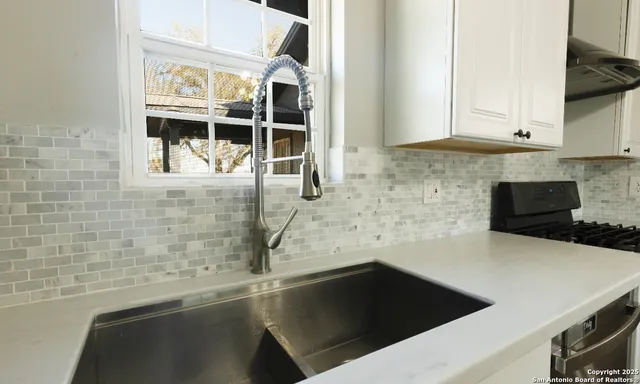 a kitchen with granite countertop a sink and white cabinets