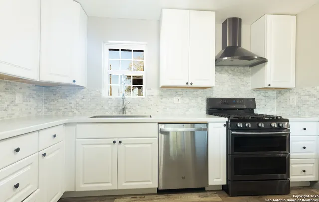 a kitchen with granite countertop white cabinets and stainless steel appliances