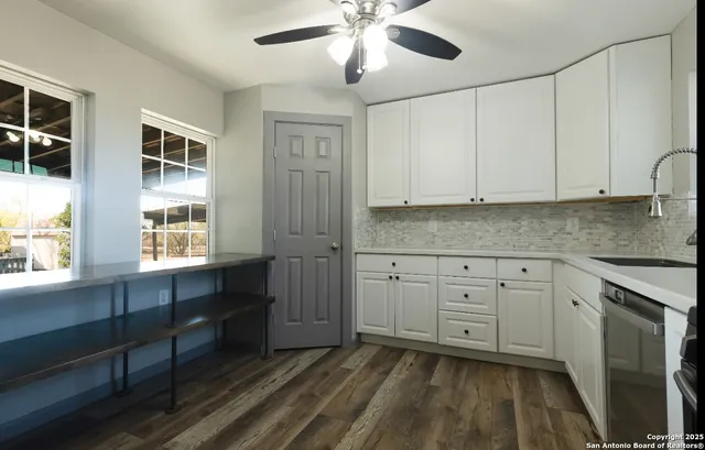 a kitchen with stainless steel appliances granite countertop a stove a sink and white cabinets with wooden floor