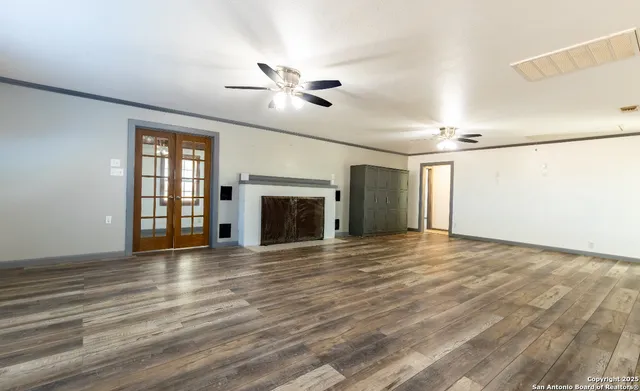 a view of an empty room with window and wooden floor