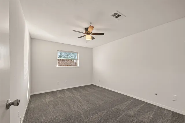 an empty room with a ceiling fan and a window