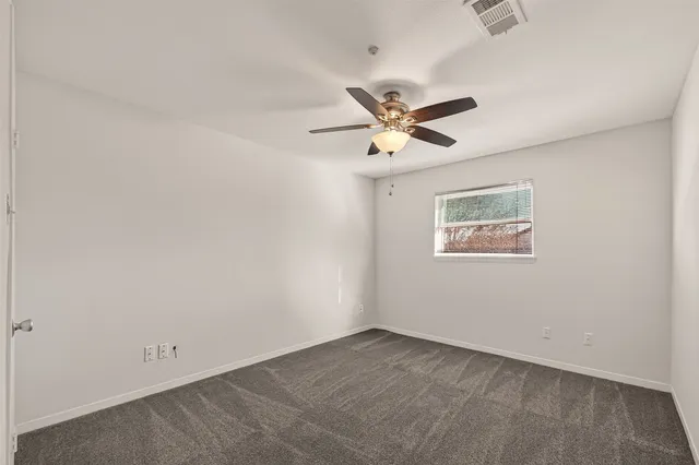 an empty room with a window and a fan