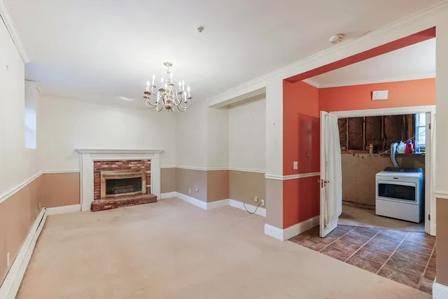 a view of a livingroom with a fireplace a chandelier and windows
