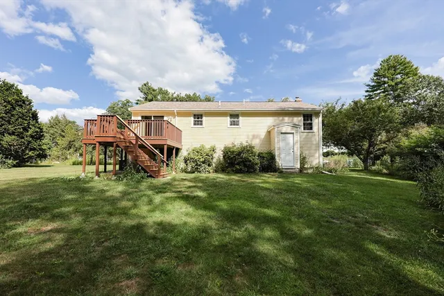 a view of a house with a big yard potted plants and large tree