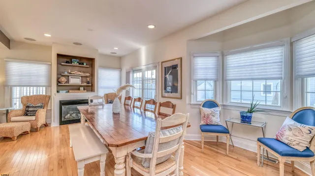 a dining room with wooden floor and large windows