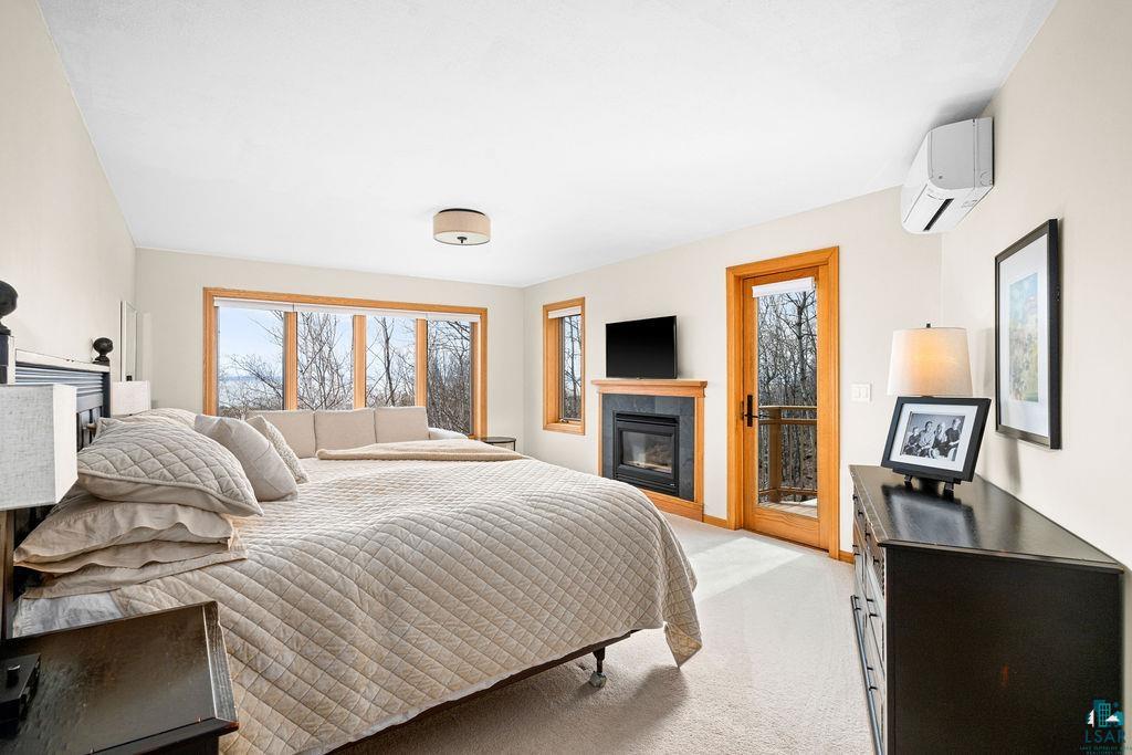 4856 Kingston Street Duluth, MN 55804 - Photo 28 of 88 Spacious room featuring multiple windows, a wood-framed glass door, a built-in fireplace with a dark stone surround, and light-colored carpeting